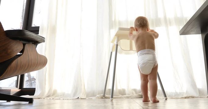 Adorable little boy moves his high chair indoors