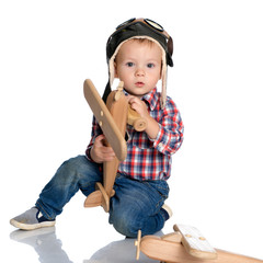 A little boy in a pilot's cap and a wooden plane in his hand