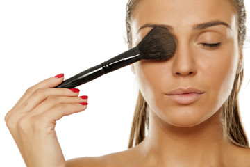 Young woman applying a powder foundation with brush on her face