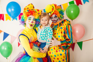 Obraz na płótnie Canvas a terrible clown and a good clown with a child. Halloween. The crazy clown and clowness. Little girl