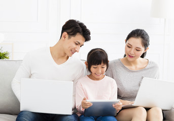 Happy asian family with laptop on sofa.