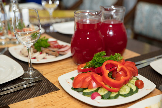 festive served table in restaurant. vegetable plate and fruit drink in jug