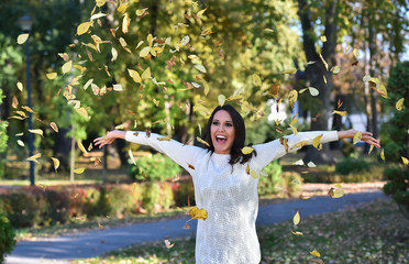young woman throw leaves in a park in autumn
