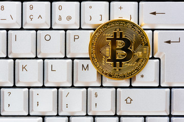 Golden color bitcoin on a gray computer keyboard