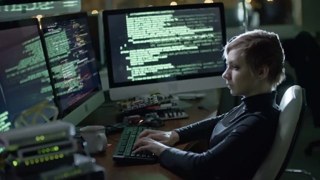 Cinemagraph of young woman with blonde short hair sitting at desk with multiple screen computers