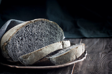 Homemade black coal bread on a wooden table, horizontal, copy space