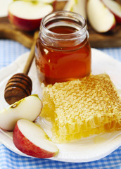 Honeycombs with honey, honey in glass jar and slices of ripe apples on plate