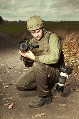 Fototapeta premium Photographer in war conflict field zone capturing video