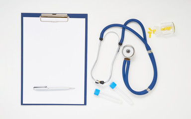 Doctor table with medicines, stethoscope, clipboard and pen, top view