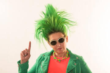 A caucasian girl in a green dress and with green hair is preparing for the holidays. Suit of the teacher of primary classes. The concept of happy holidays and good mood.