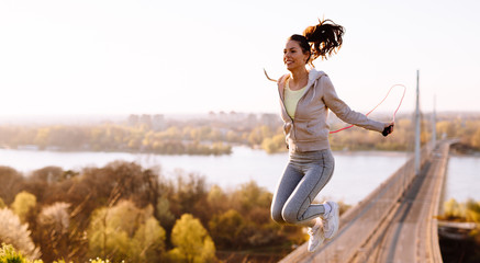 Active woman jumping with skipping rope outdoors