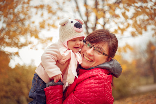 Mom with a child playing in autumn park.