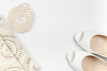 Female white shoes, bag, belt and pearl necklace on a white background