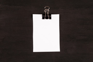 Blank sheet of white paper with paper clip on a black background