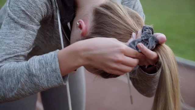 The athlete tied her hair in the tail. Running Women tying up hair before run