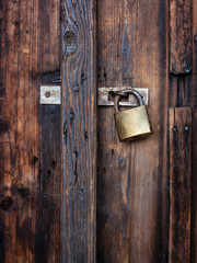 Old dark brown wooden door with padlock.