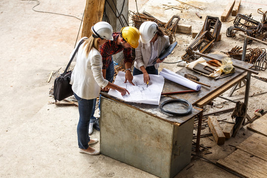 Two female inspectors and architects discuss with head engineer about construction project.