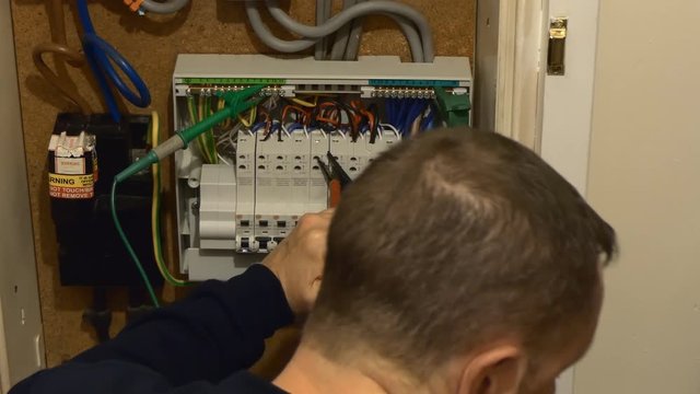 Electrician opened fuse box and testing house electrical circuits for faults