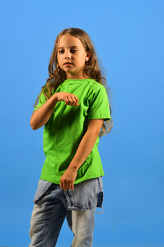 Girl with serious face on blue background. Childhood and style
