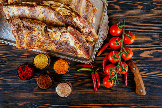 raw marinated pork ribs and tomatoes of garlic pepper on a black board