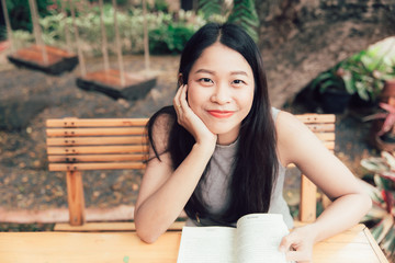 Enjoy relax times with reading book, Asian women Thai teen smile with book in coffee shop vintage color tone