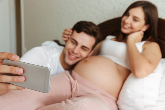 Young pregnant couple taking selfie