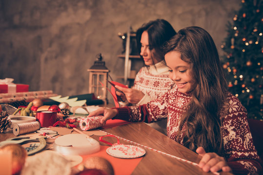 Adorable cute girl with mom doing handcraft activity, enjoying, desktop is full of materials. Happiness, upbringing, childhood, friendship, leisure, hobby, traditions x mas noel concept