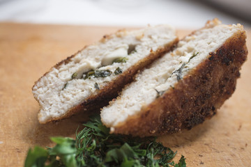 Fried cutlets with cheese and greens on a wooden background