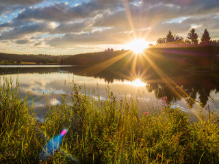 Sonneaufgang über einem See im Harz mit Reflexion Blendenfleck