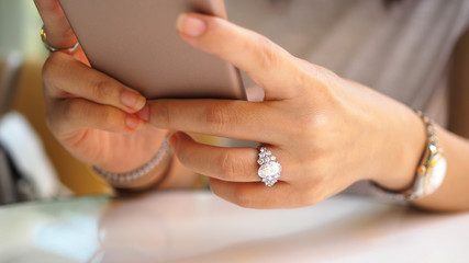 Woman hand close up on diamond ring using a mobile phone. (Selected focus)