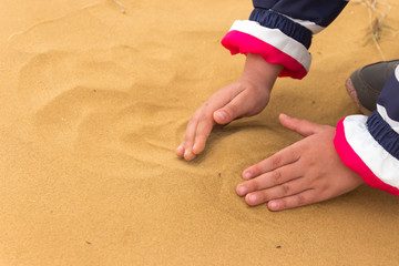 Yellow sand with kids hands on it