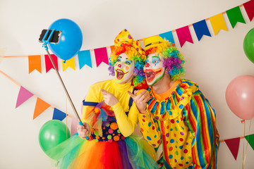 Two clowns boy and girl on Holiday with a selfie stick. Birthday of the child.