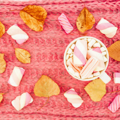 Beauty pink concept of marshmallow with cappuccino mug, pen and notebook on pink cloth background. Flat lay, top view.