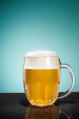 glass of cold frothy lager beer on an old wooden table