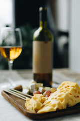 Glass with wine and plate with cheese and grapes