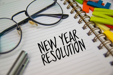 Business concept, Eye Glass over the notebook written NEW YEAR RESOLUTION