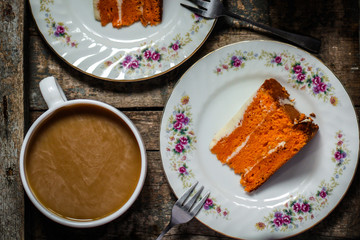 piece of orange cake with white cream on a wooden table