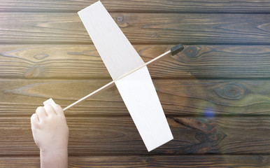 A wooden airplane in a hand holds a child on a wooden background