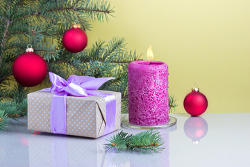 Новогодние подарки и свеча на жёлтом фоне
