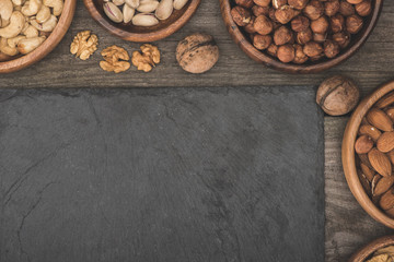 Fototapeta na wymiar nuts in bowls and slate board