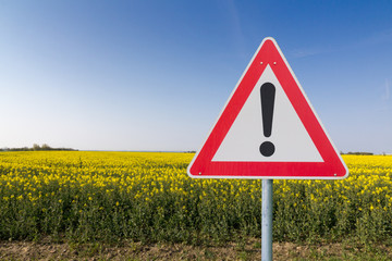 Achtung Schild vor einem Rapsfeld