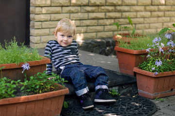 A little boy is sitting on the doorstep of the house