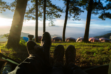 Feet of two friends or a couple in the entrence of a tent while watching the sunrice. Trekking, camping, nature, outdoors concept. Copy space