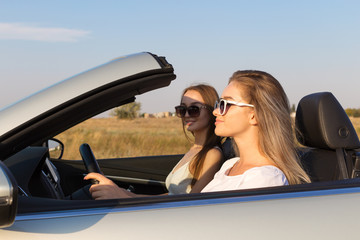 Two attractive young women in a cabriolet car