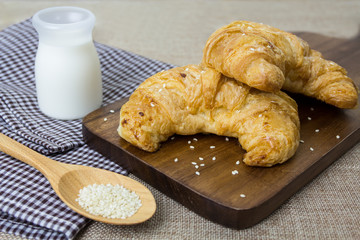Fresh croissants with milk and white sesame on fabric background