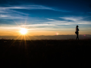 The girl is walking away from the sun in silhouette moment on the top of Mon Jong Mountain, Chiangmai, Thailand.