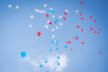 Balloons of red blue and white colors flying in the blue sky with clouds
