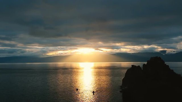 Beautiful colorful sunset at the Lake Baikal with dramatic clouds and sun shining. Full color clouds of twilight sky.