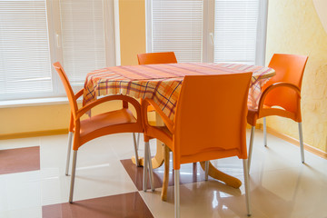 Four orange chairs and table with checkered tablecloth in the dining room