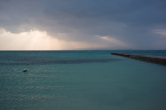雲から夕陽が覗く海